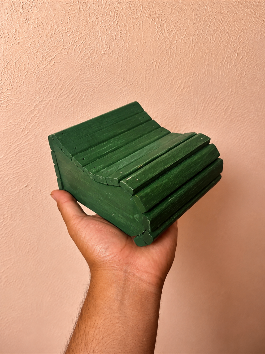 Small green painted slatted wooden chair held by hand